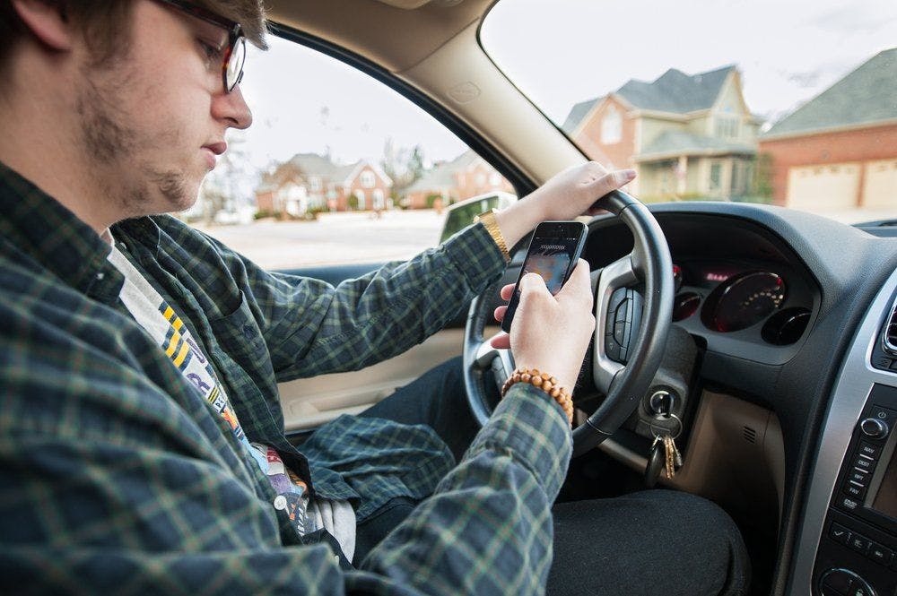 stock photo of teen driving and texting